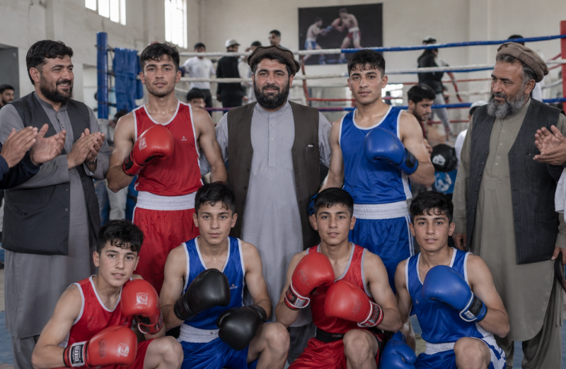 Boxers and sports officials gathered beside a boxing ring during a provincial championship in Ghazni