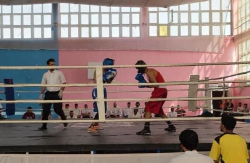 Boxers and sports officials gathered beside a boxing ring during a provincial championship in Ghazni