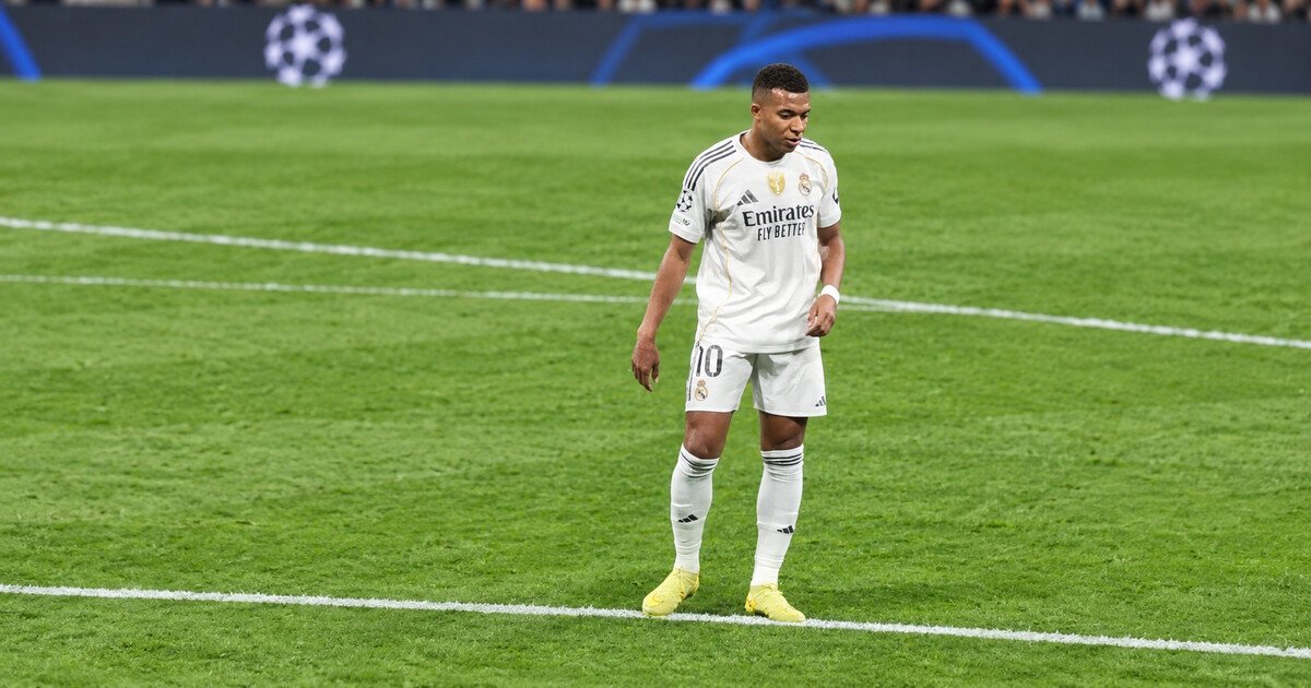 Kylian Mbappé standing on the pitch in Real Madrid’s white kit